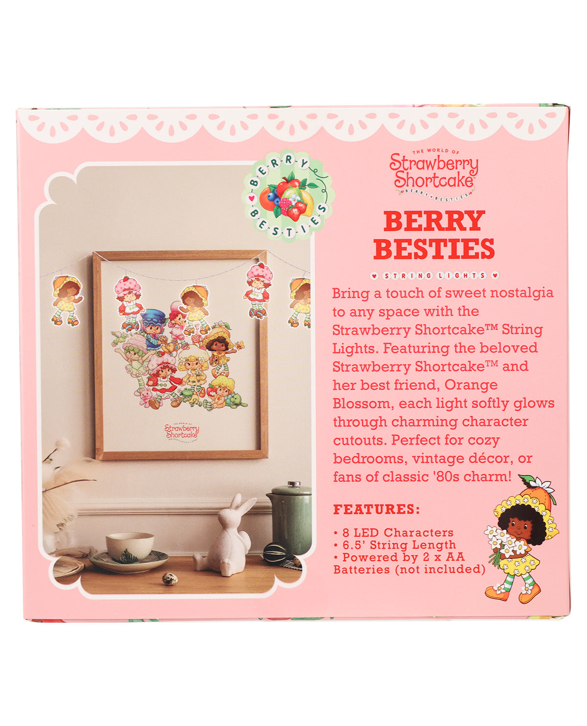 Front of a Strawberry Shortcake 'Berry Besties' string lights kit box, showing a framed preview of the multicolor LED character lights and product features on a pink background.