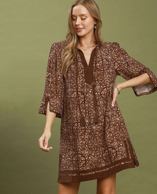 Woman wearing a brown patterned dress against an olive green background