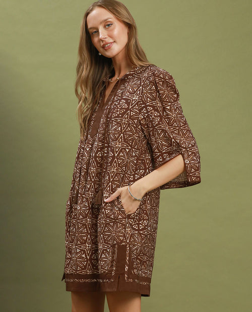 Woman wearing a brown patterned dress against an olive green background