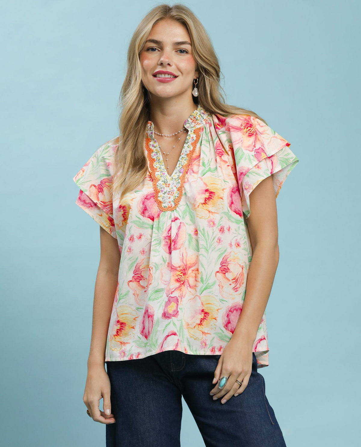 Woman wearing a colorful floral blouse against a light blue background