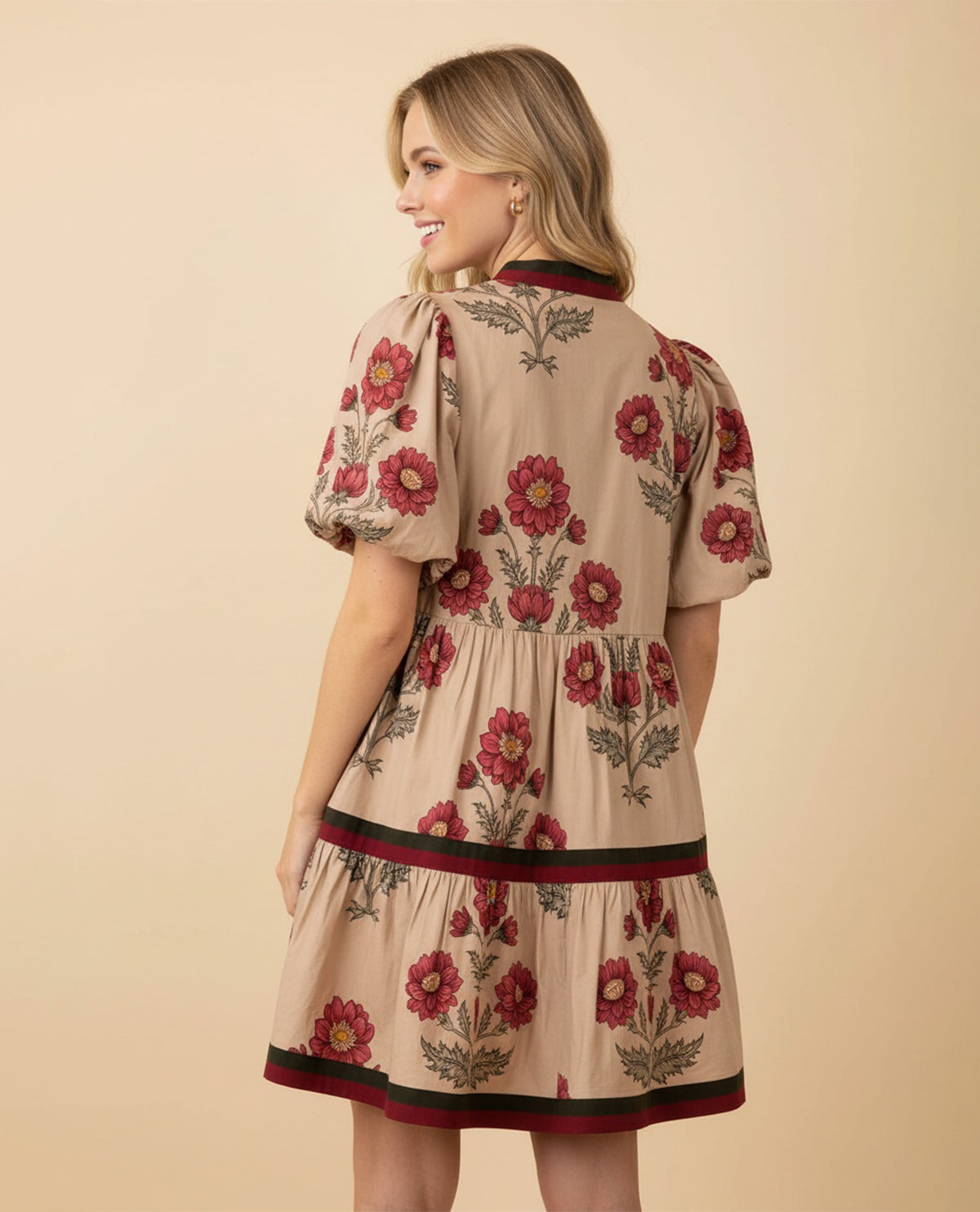 Woman wearing a beige dress with floral embroidery on a beige background