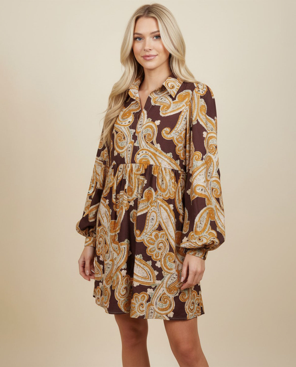 Woman wearing a brown and gold paisley dress on a beige background