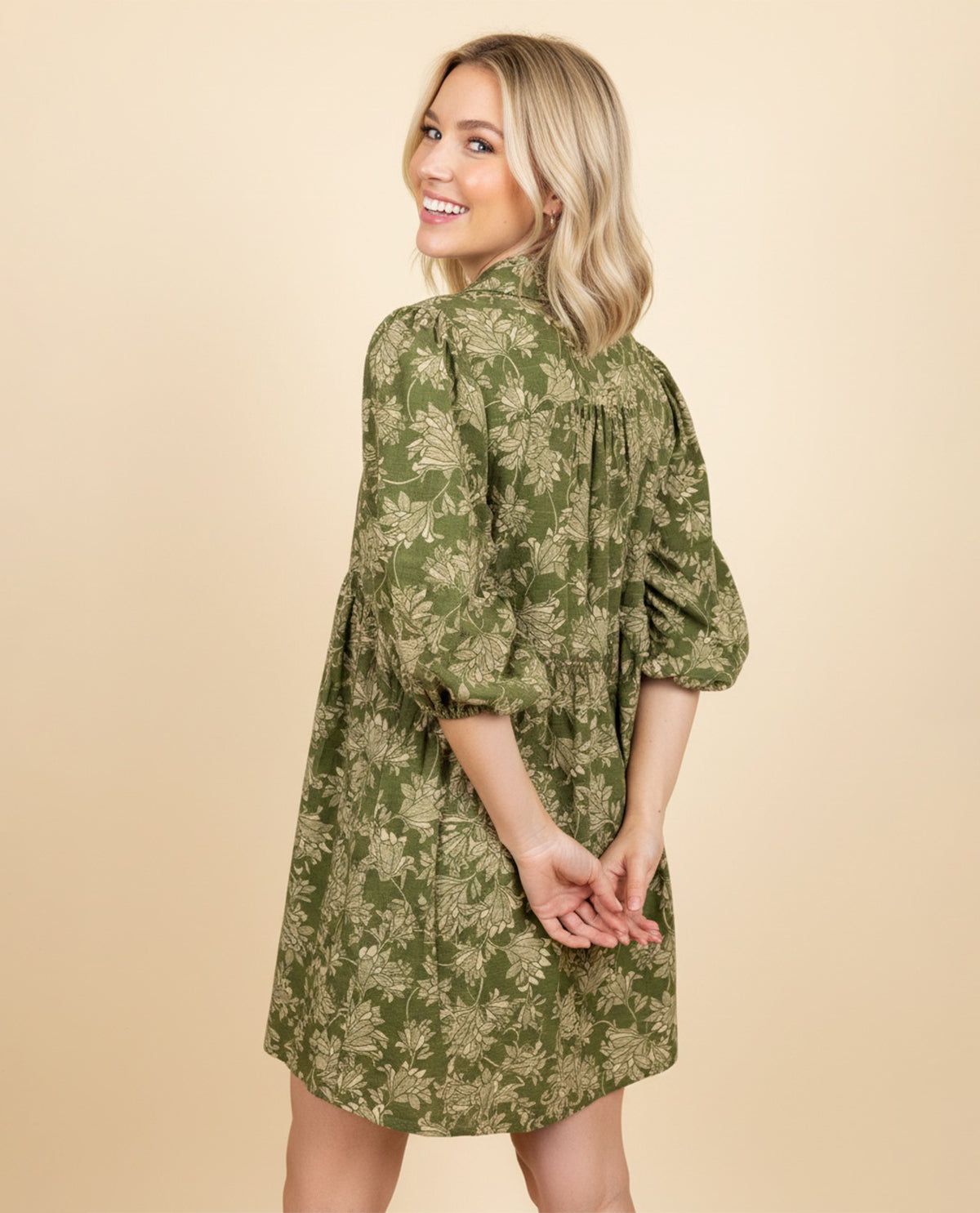 Woman wearing a green floral dress against a beige background