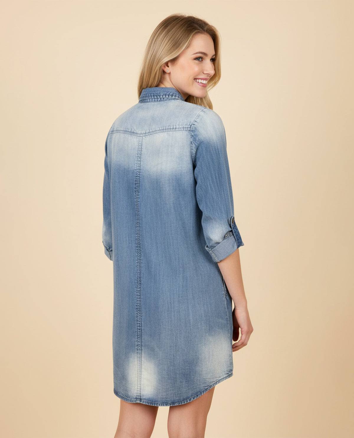 Woman wearing a denim dress on a beige background