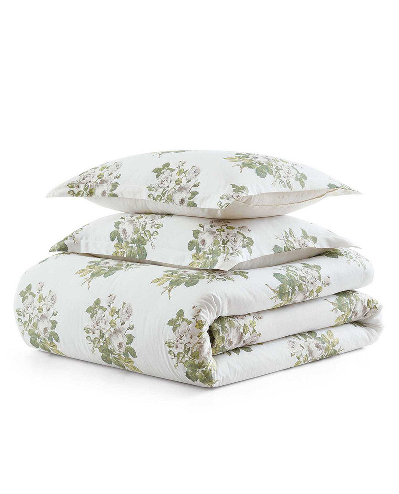 A folded bedding set with two matching pillows and a quilted comforter, featuring a white background with a green and white floral pattern.