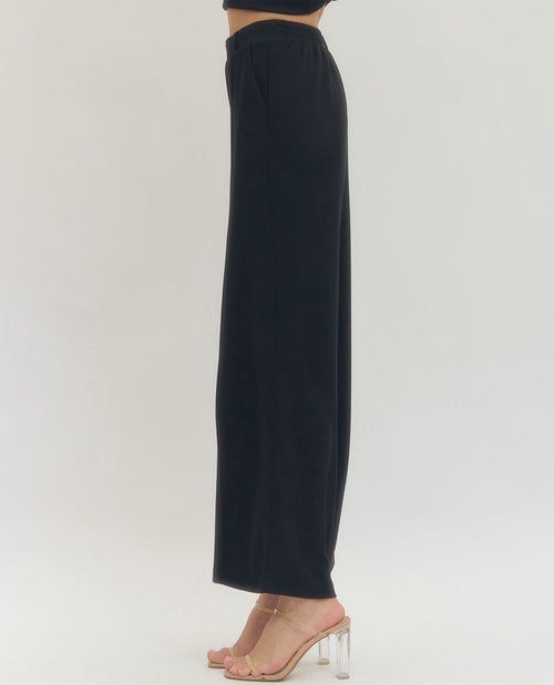 Black wide-leg pants worn by a person on a white background