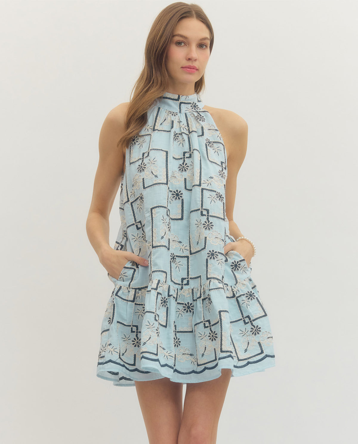 Woman wearing a light blue dress with black geometric pattern on a white background