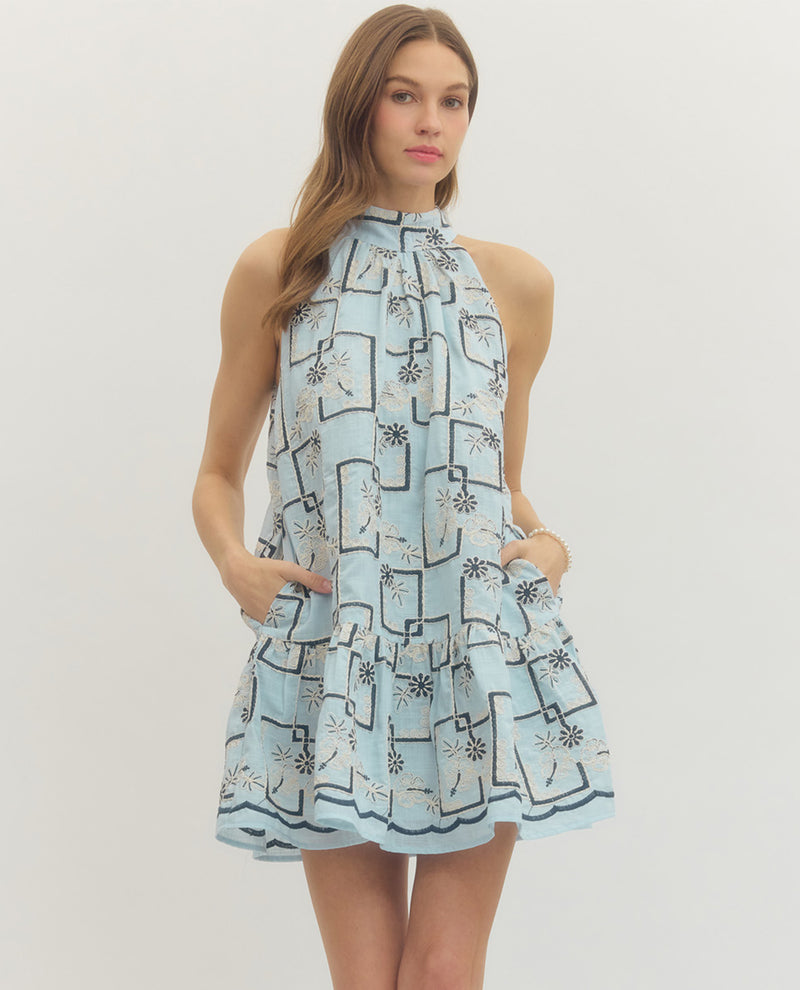 Woman wearing a light blue dress with black geometric pattern on a white background