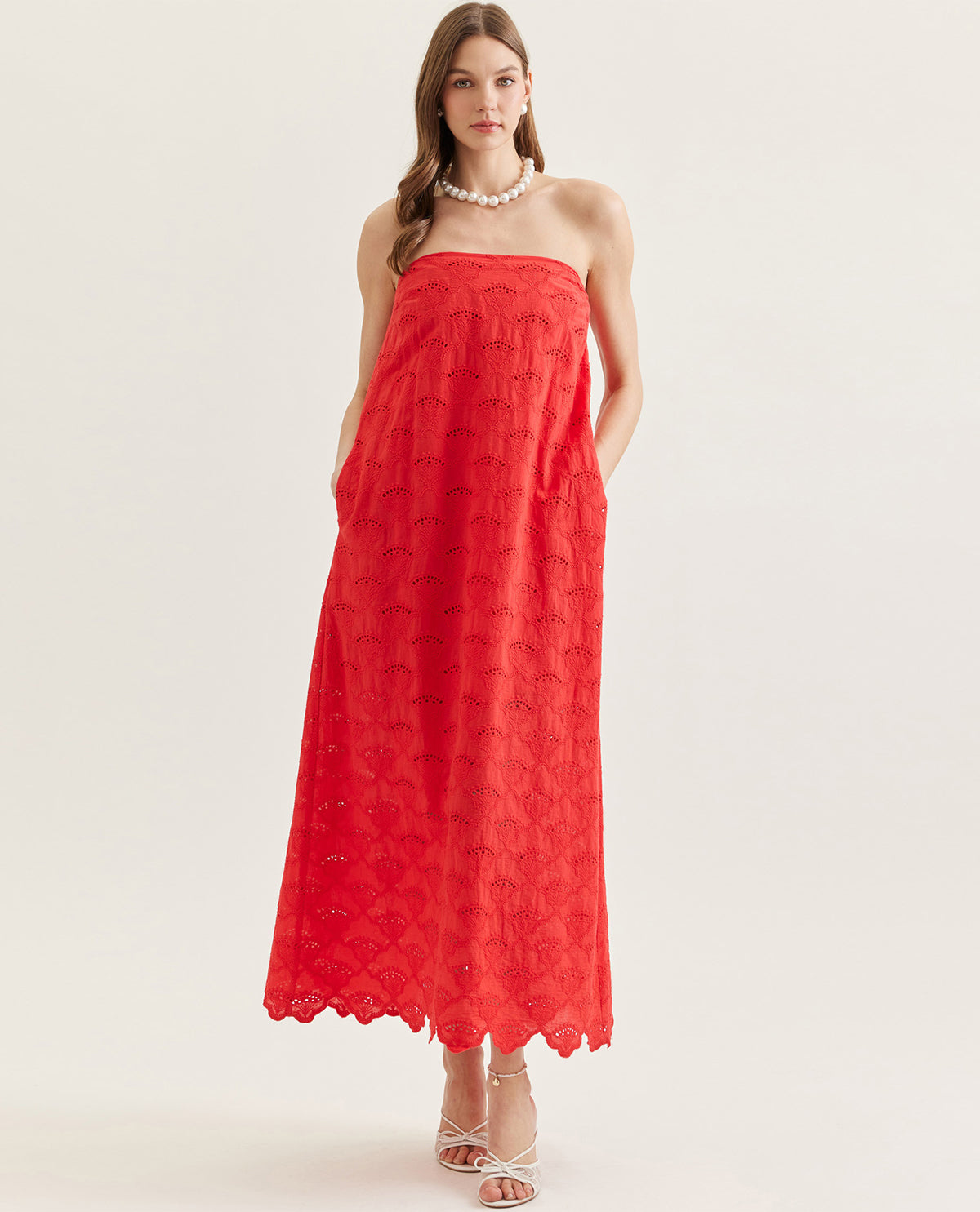 Woman wearing a red strapless dress on a white background