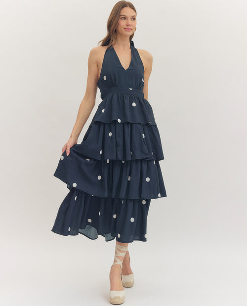 Woman wearing a navy blue dress with white polka dots on a white background