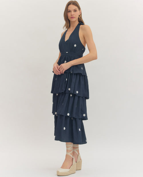 Woman wearing a navy blue dress with white buttons on a white background