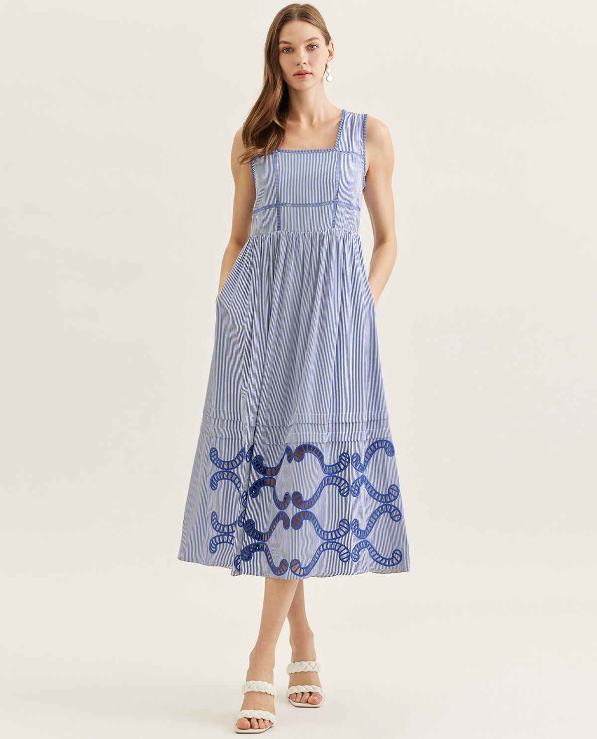 Woman wearing a blue dress with white patterns on a light background