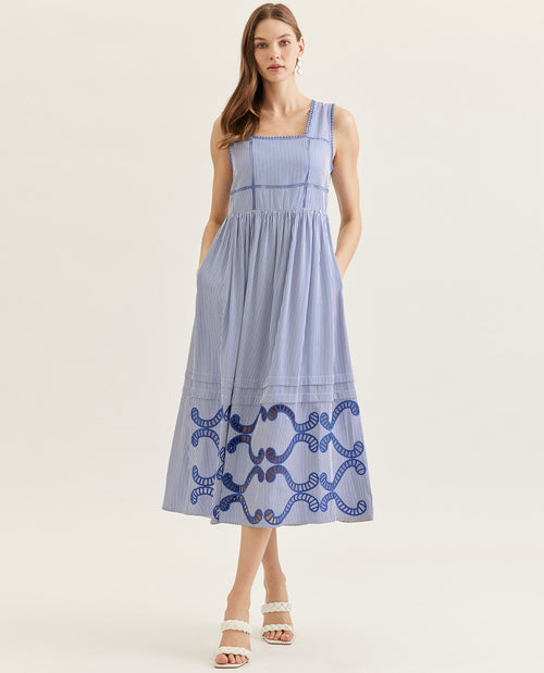 Woman wearing a blue dress with white patterns on a light background