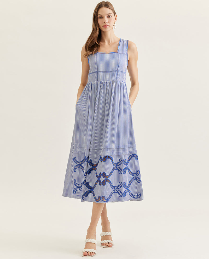 Woman wearing a blue dress with white patterns on a light background
