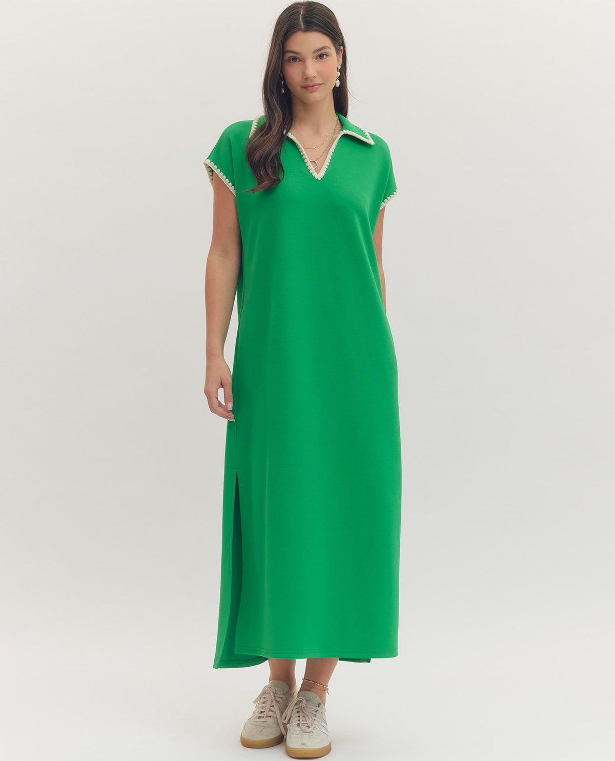 Woman wearing a green dress with white trim on a white background