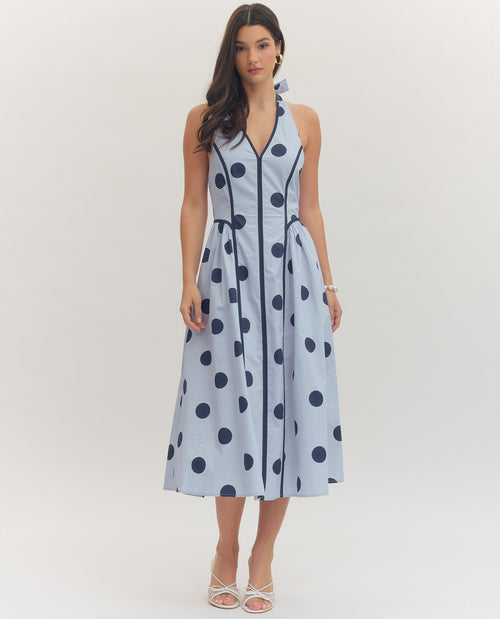 Woman wearing a light blue dress with dark blue polka dots on a white background