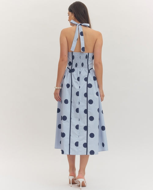 Woman wearing a light blue dress with dark blue polka dots on a white background