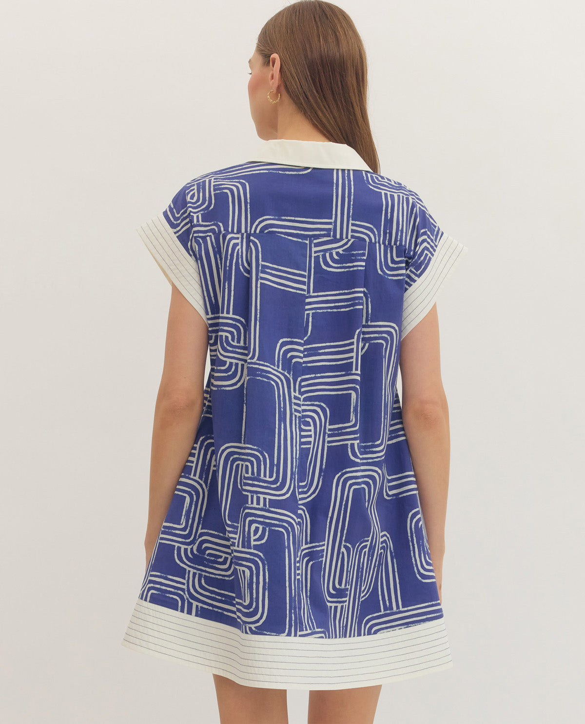 Woman wearing a blue and white patterned dress on a plain background