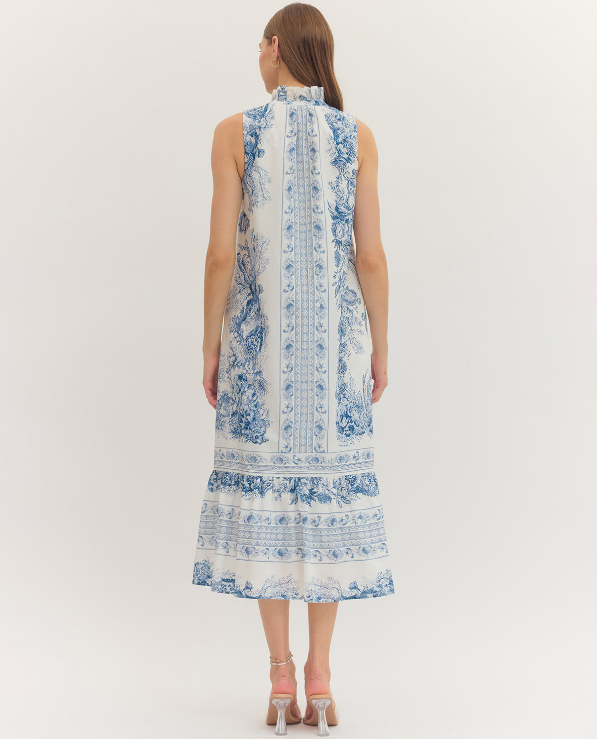 Woman wearing a sleeveless dress with blue floral pattern on a white background