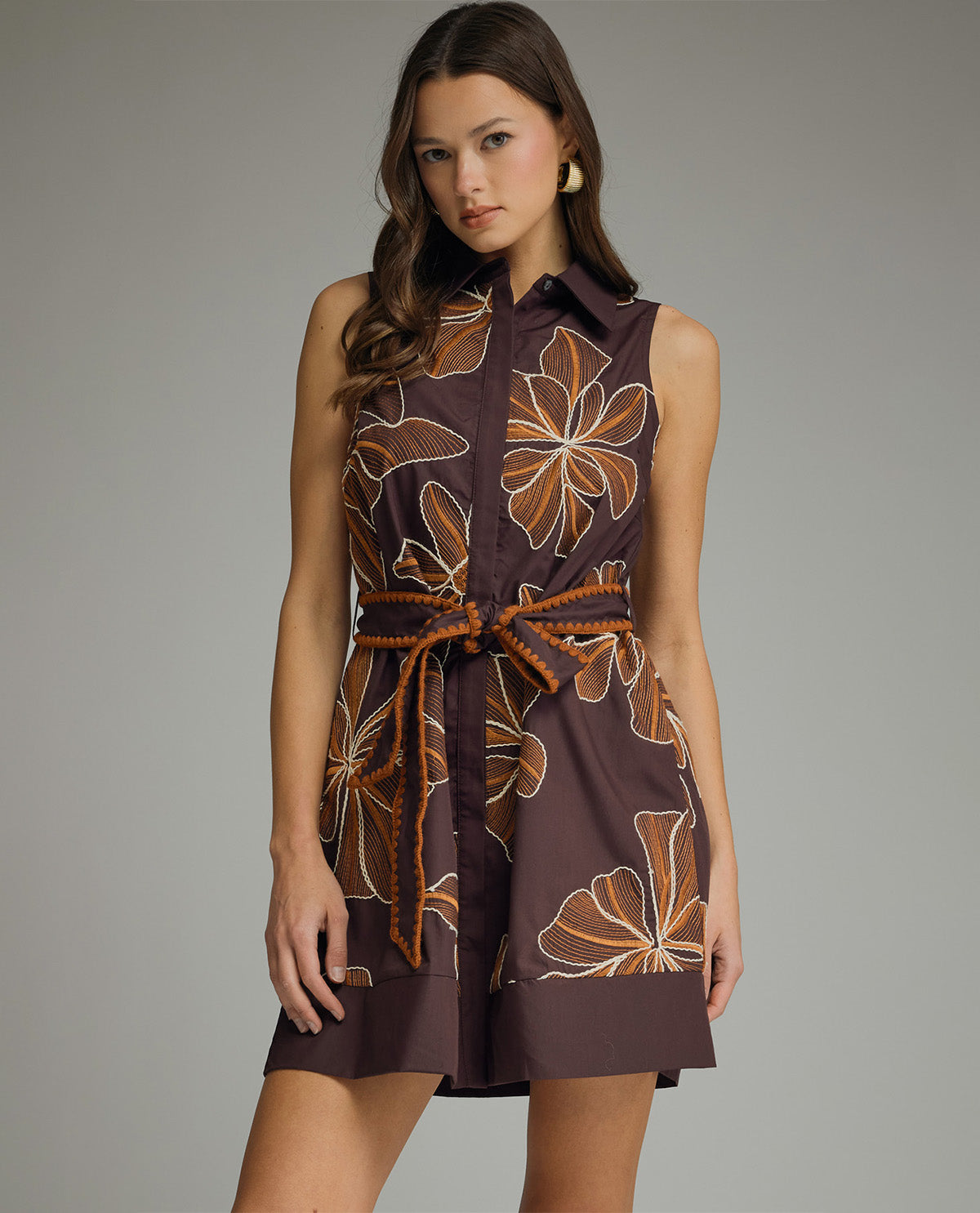 Woman wearing a brown dress with floral patterns on a gray background