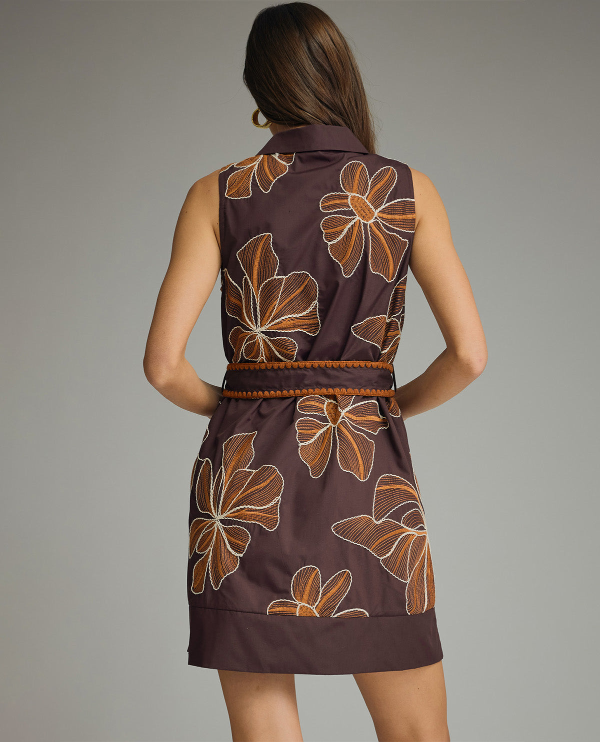 Woman wearing a brown dress with floral patterns on a gray background