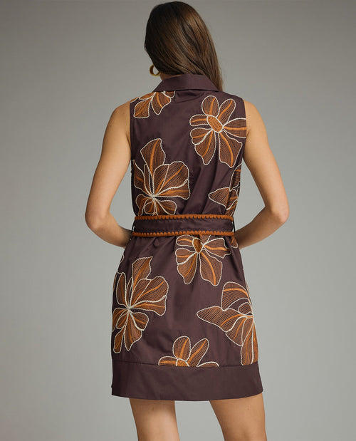 Woman wearing a brown dress with floral patterns on a gray background