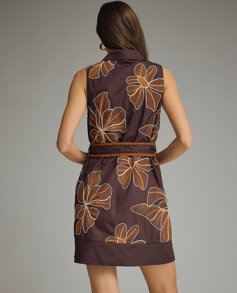 Woman wearing a brown dress with floral patterns on a gray background
