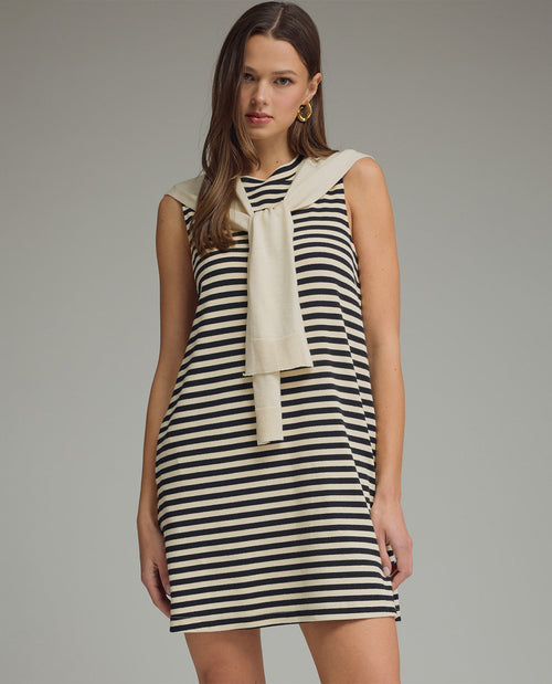 Woman wearing a black and white striped dress with a beige scarf on a gray background