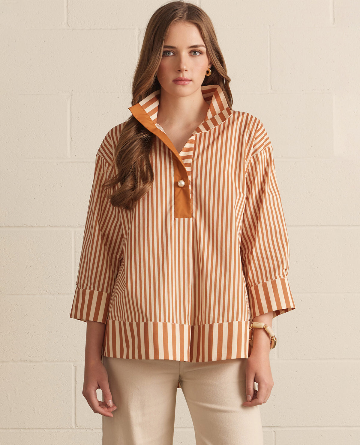 Woman wearing a striped shirt with a collar against a light background