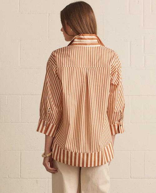 Woman wearing a striped shirt against a white brick wall