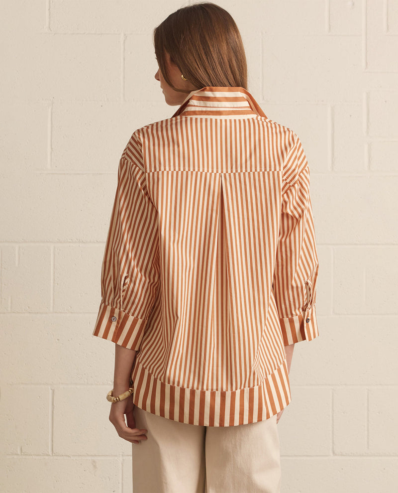 Woman wearing a striped shirt against a white brick wall