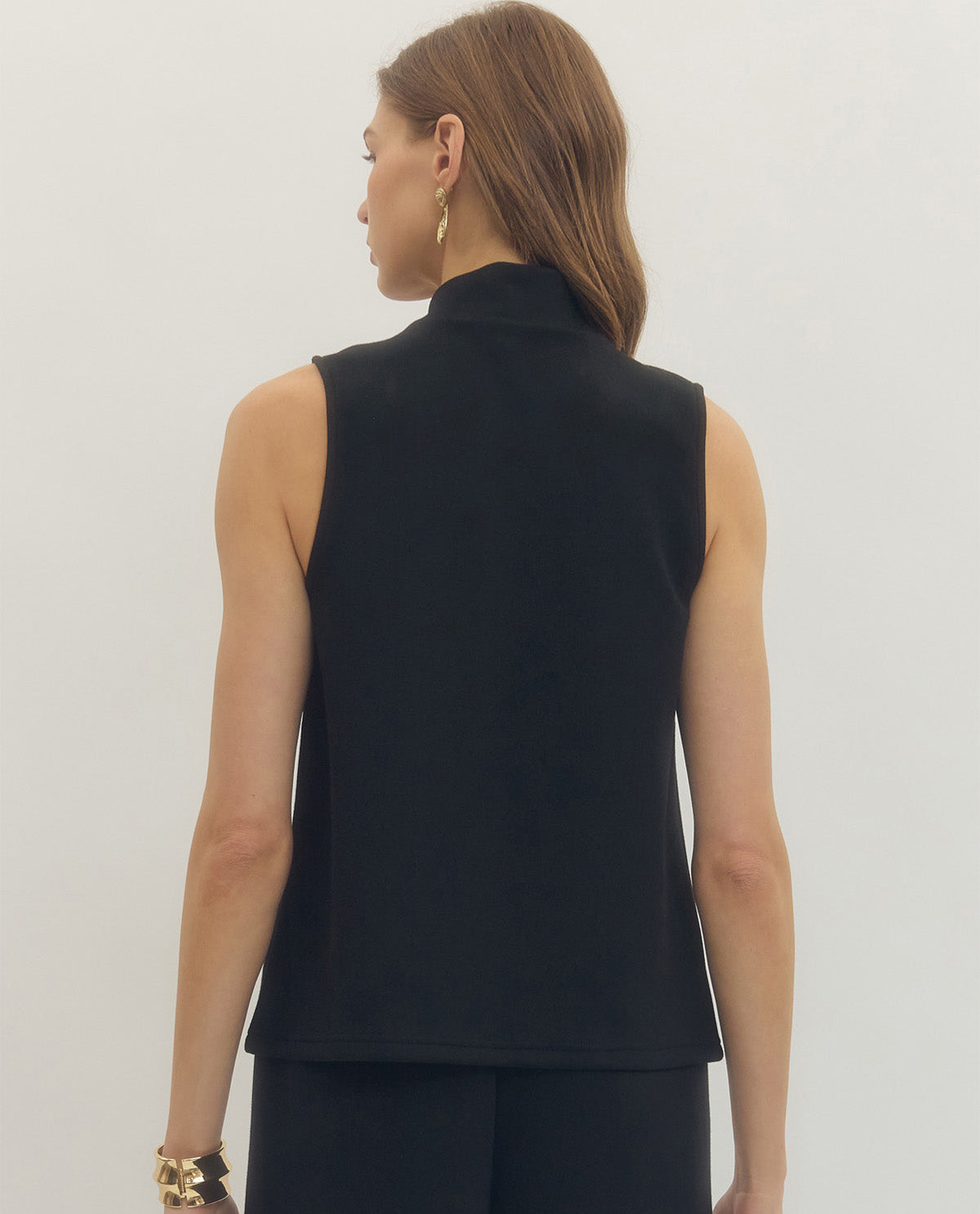 Woman wearing a black sleeveless top against a plain background