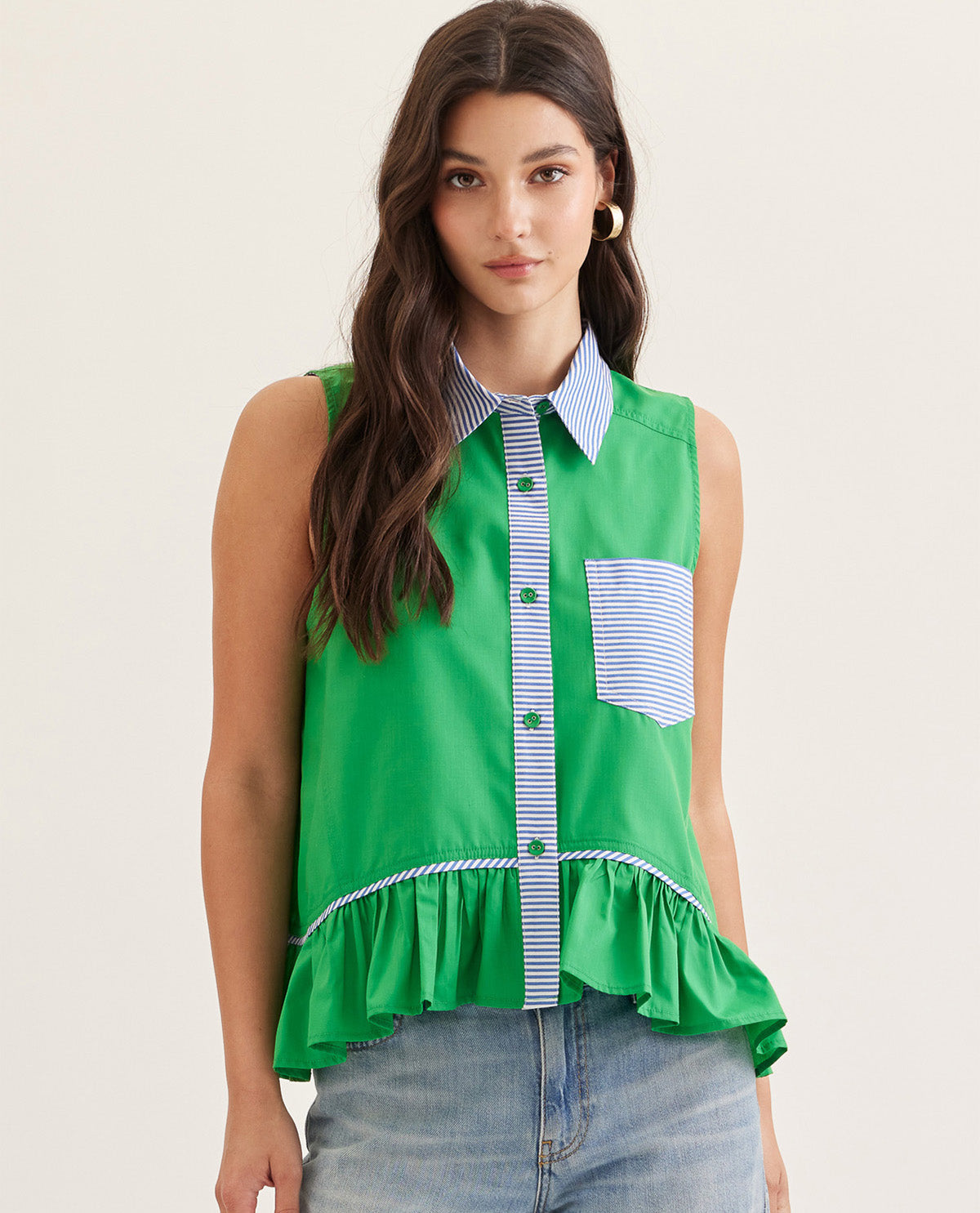 Woman wearing a green sleeveless top with a striped collar against a plain background