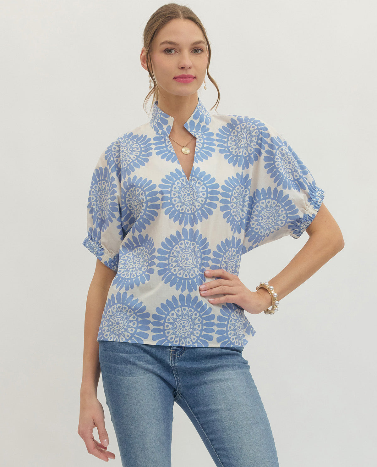 Woman wearing a blue and white floral patterned shirt with a plain background