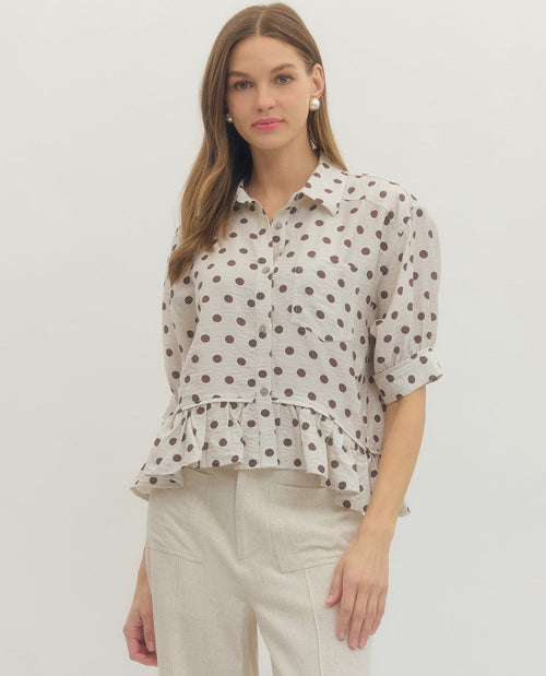 Woman wearing a polka dot blouse and beige pants on a white background