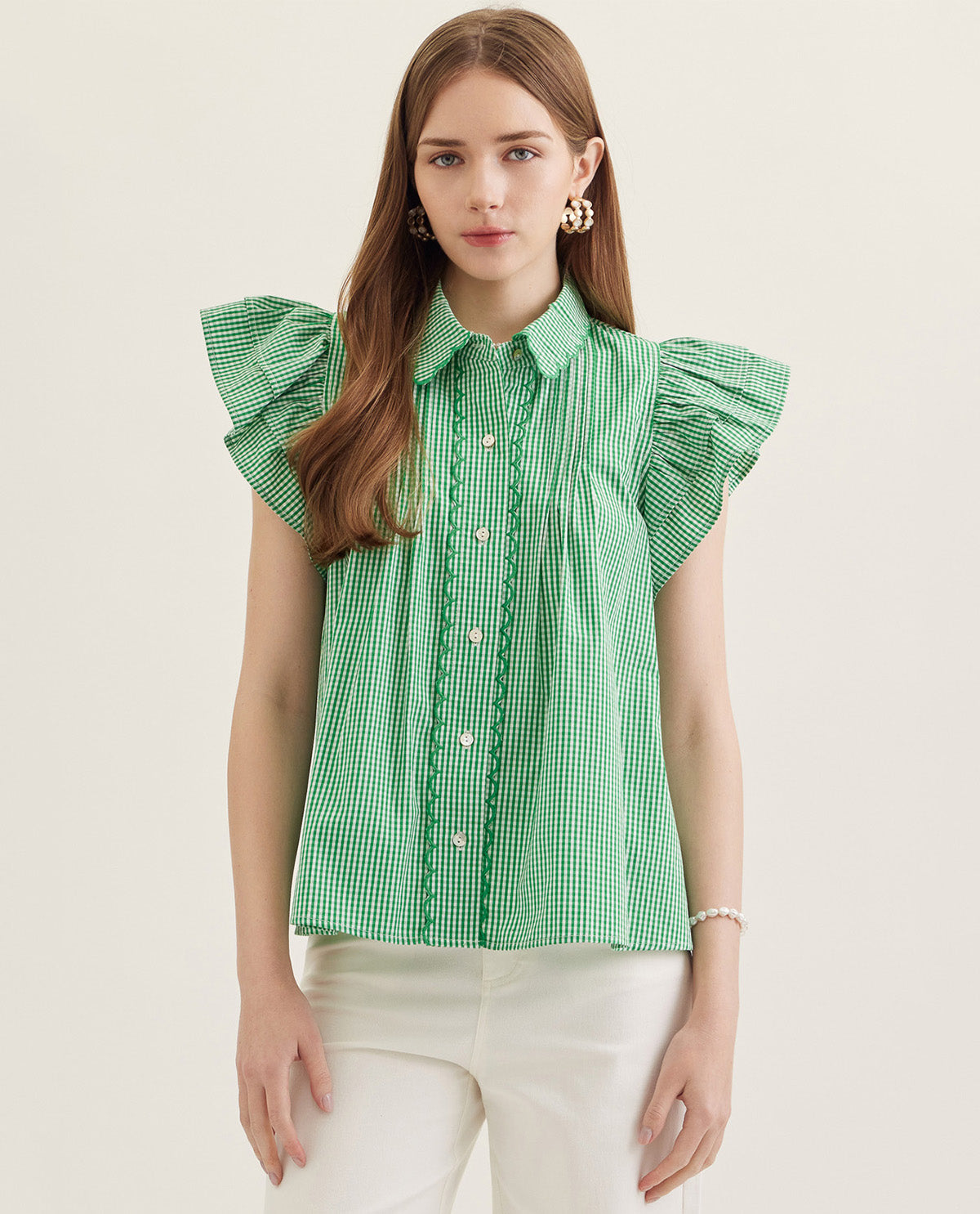 Woman wearing a green checkered blouse with ruffled sleeves on a white background