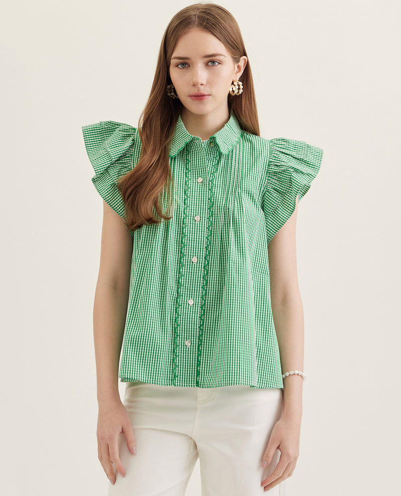 Woman wearing a green checkered blouse with ruffled sleeves on a white background