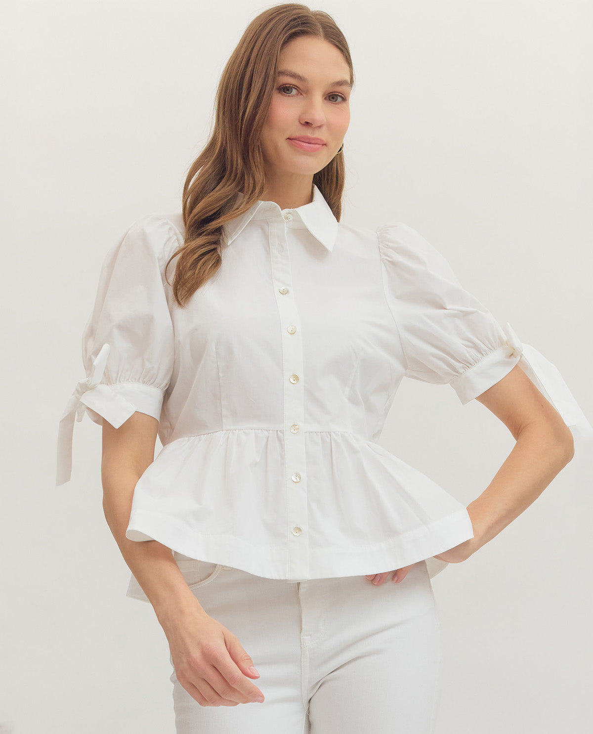 Woman wearing a white peplum blouse against a plain background