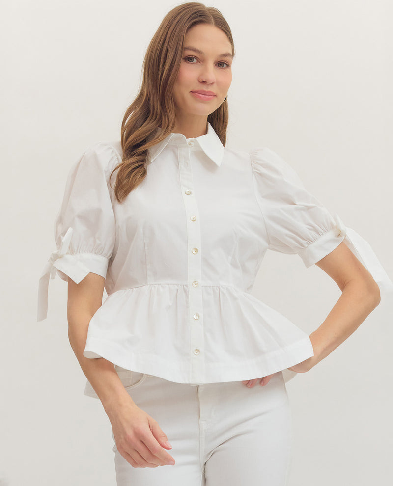 Woman wearing a white peplum blouse against a plain background