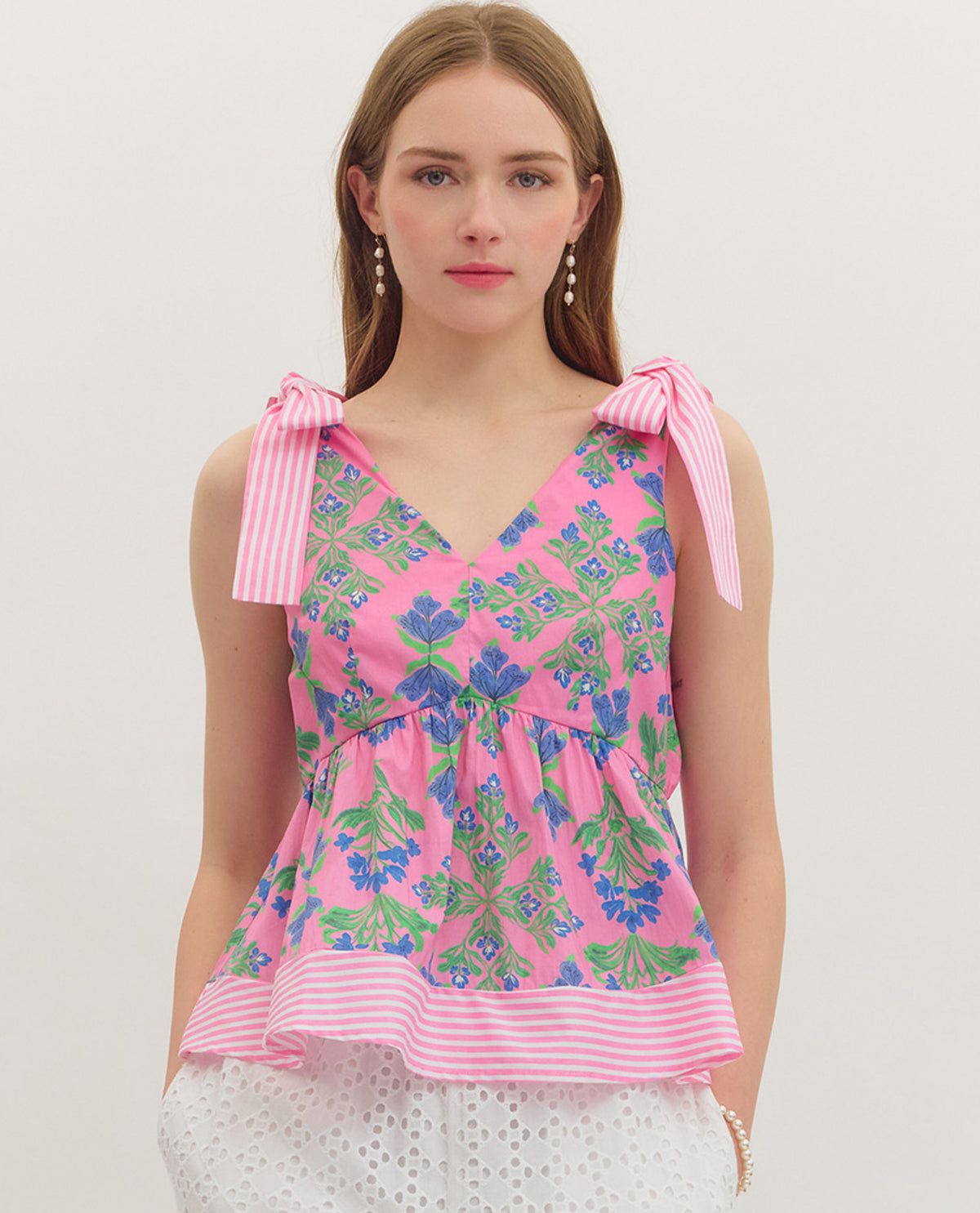 Woman wearing a pink floral top with bow straps on a white background