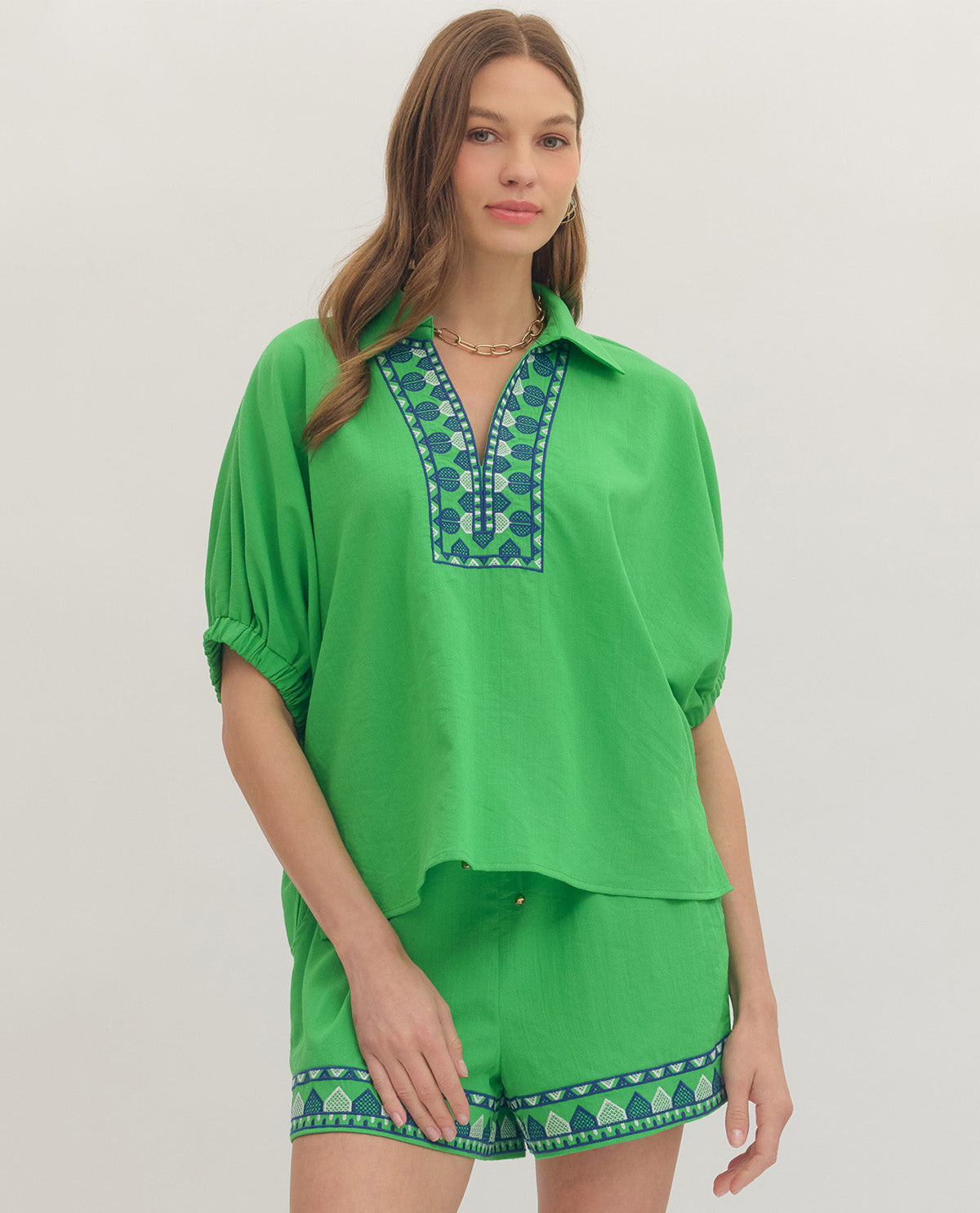 Woman wearing a green outfit with embroidered details on a white background