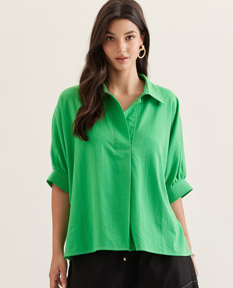 Woman wearing a green shirt against a plain background