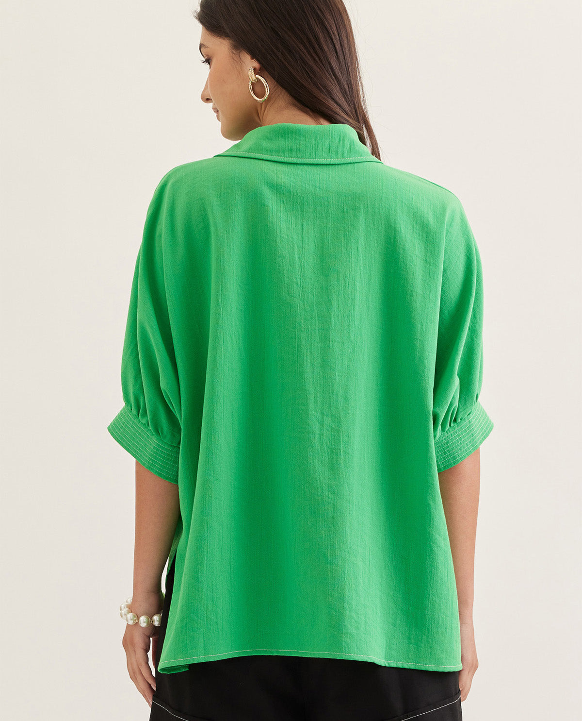 Green shirt worn by a person on a plain background