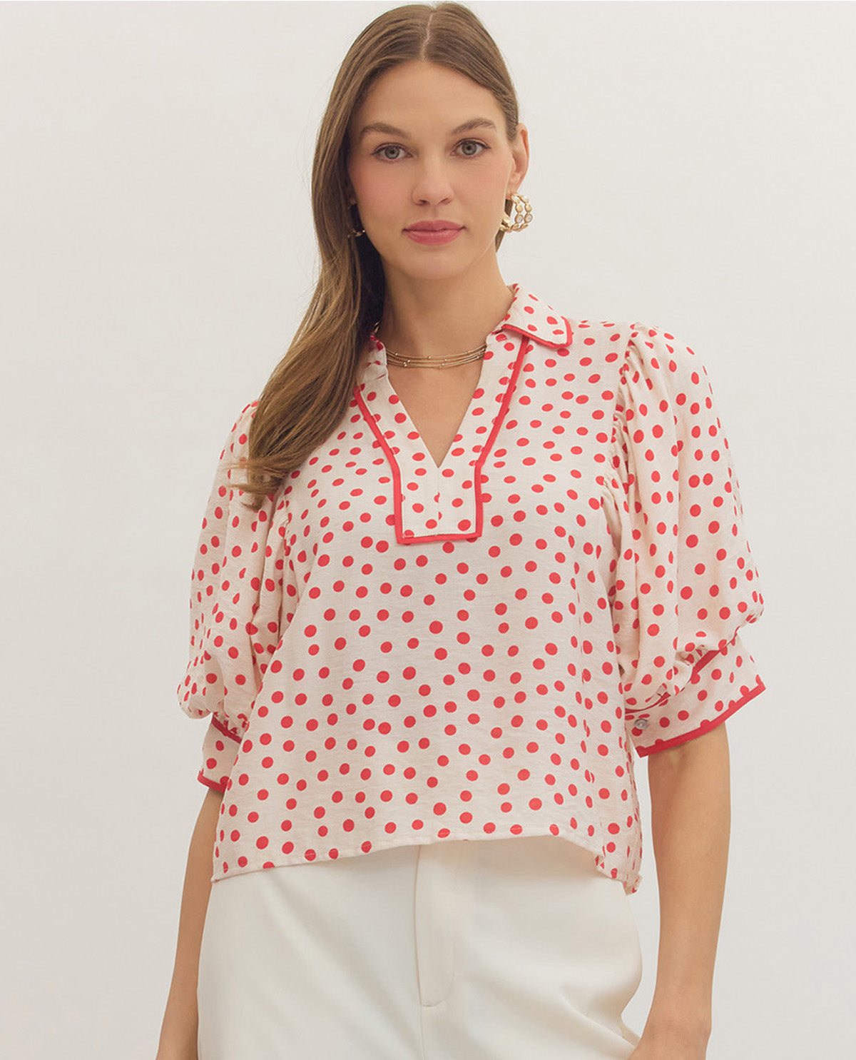 Woman wearing a red polka dot blouse against a white background