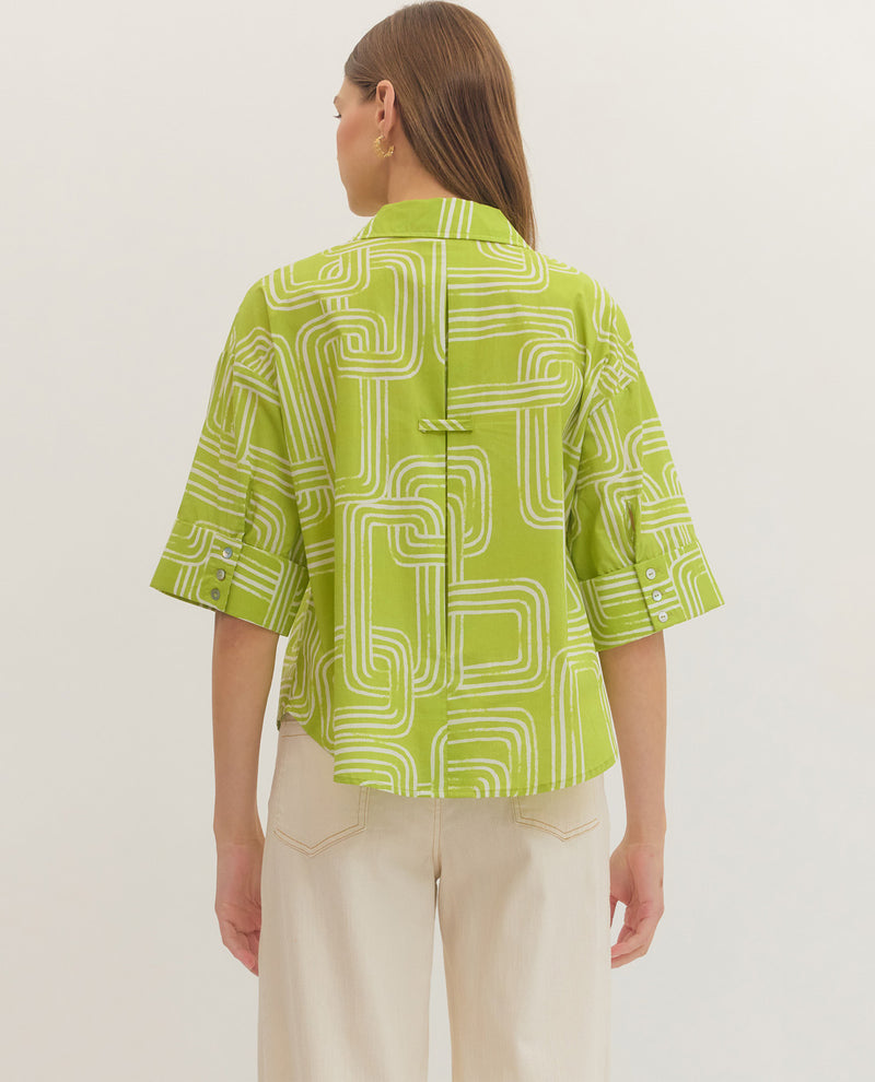Person wearing a green patterned shirt with beige pants on a white background
