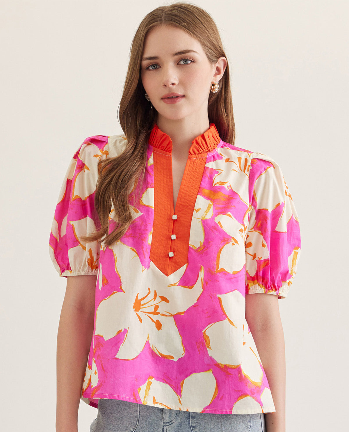 Woman wearing a colorful floral blouse with a pink background