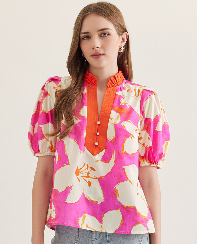 Woman wearing a colorful floral blouse with a pink background