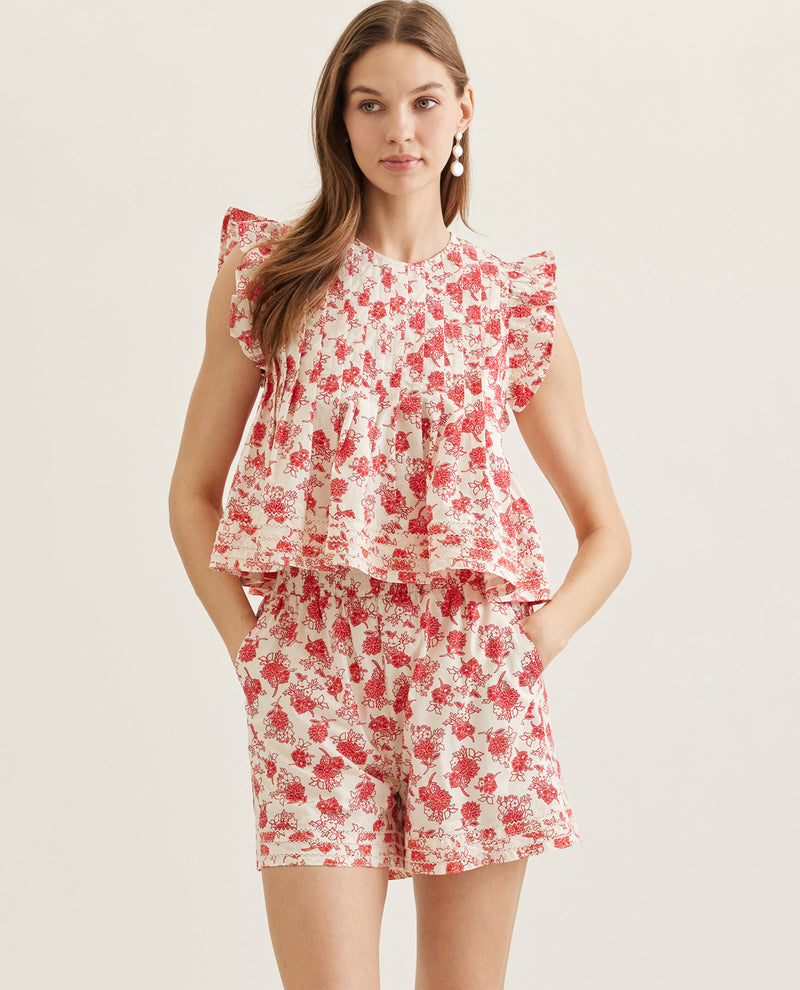 Woman wearing a red floral top and shorts set on a light background