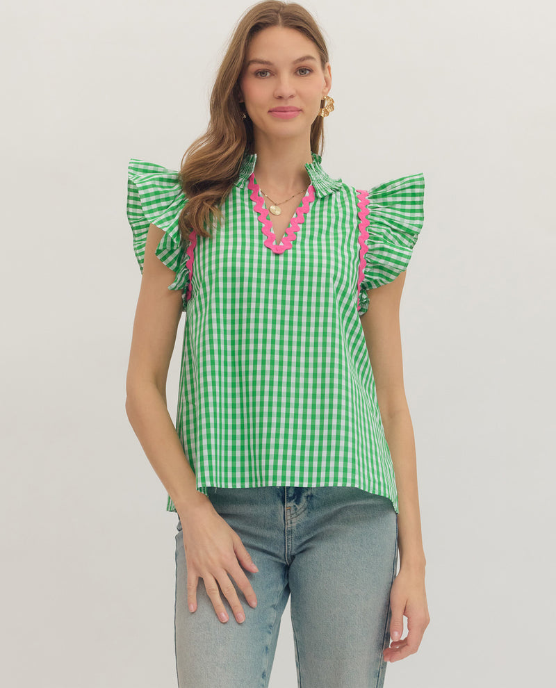 Woman wearing a green checkered top with pink accents on a plain background