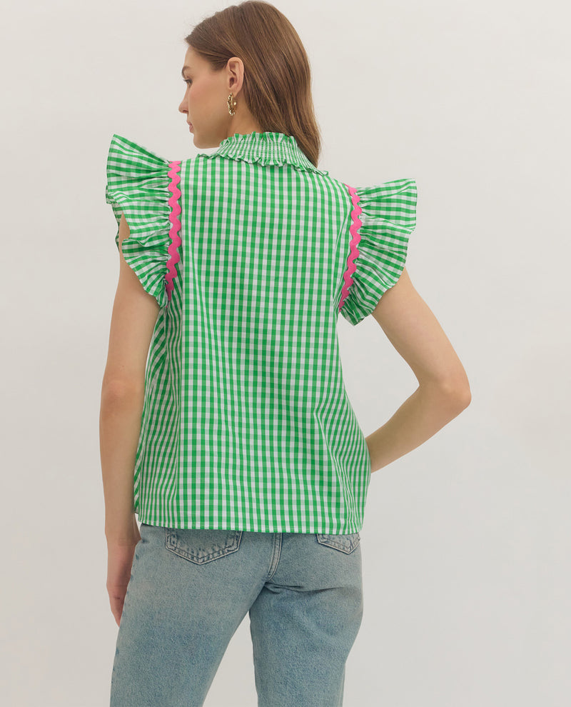 Woman wearing a green checkered shirt with pink trim on a plain background